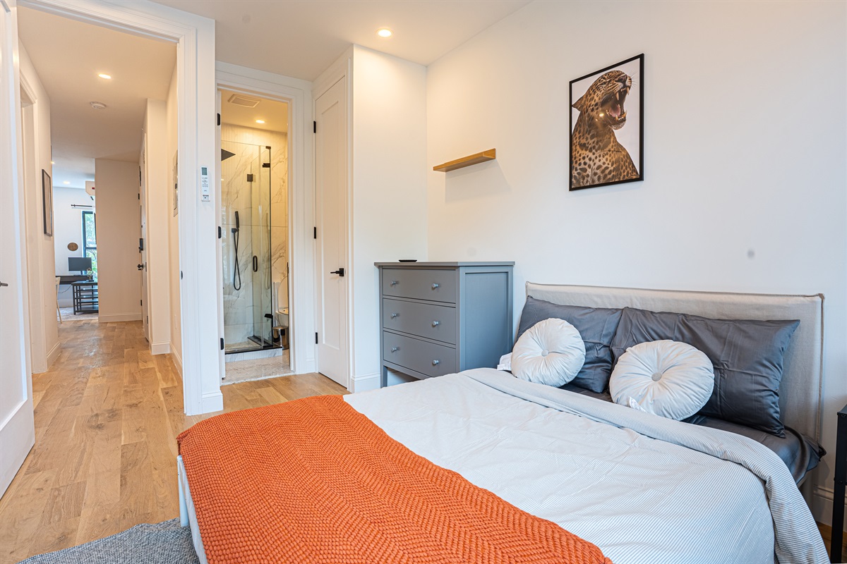 Stylish bedroom with leopard art, marble shower, and workspace view