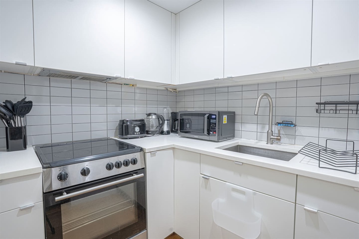 Fully equipped modern kitchen featuring stainless steel appliances, a sleek stovetop oven, microwave, coffee maker, toas