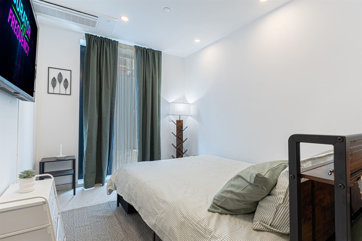 Restful bedroom with a plush queen bed, fresh linens, and a smart TV — a quiet retreat after exploring Brooklyn.