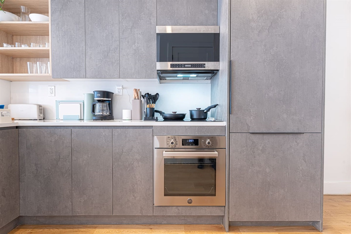 Sleek gray kitchen cabinetry with open shelving and built-in appliances — plenty of storage and prep space for home-cook