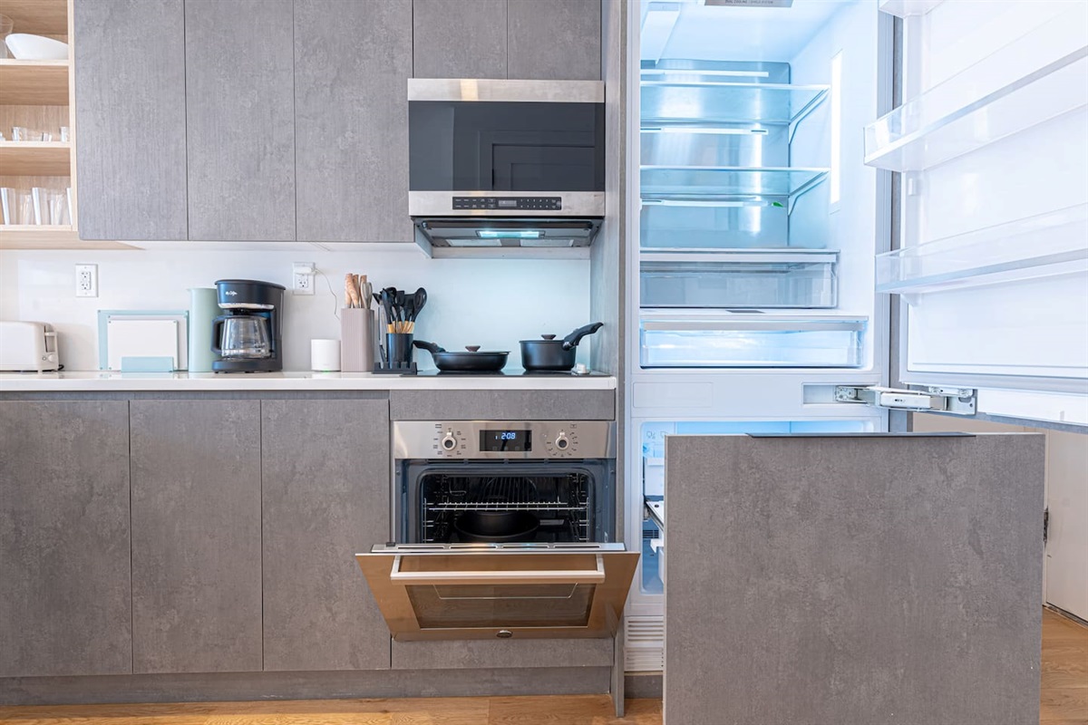 Fully equipped kitchen with stainless oven, microwave, dishwasher, and full-size fridge — cook in just like home.