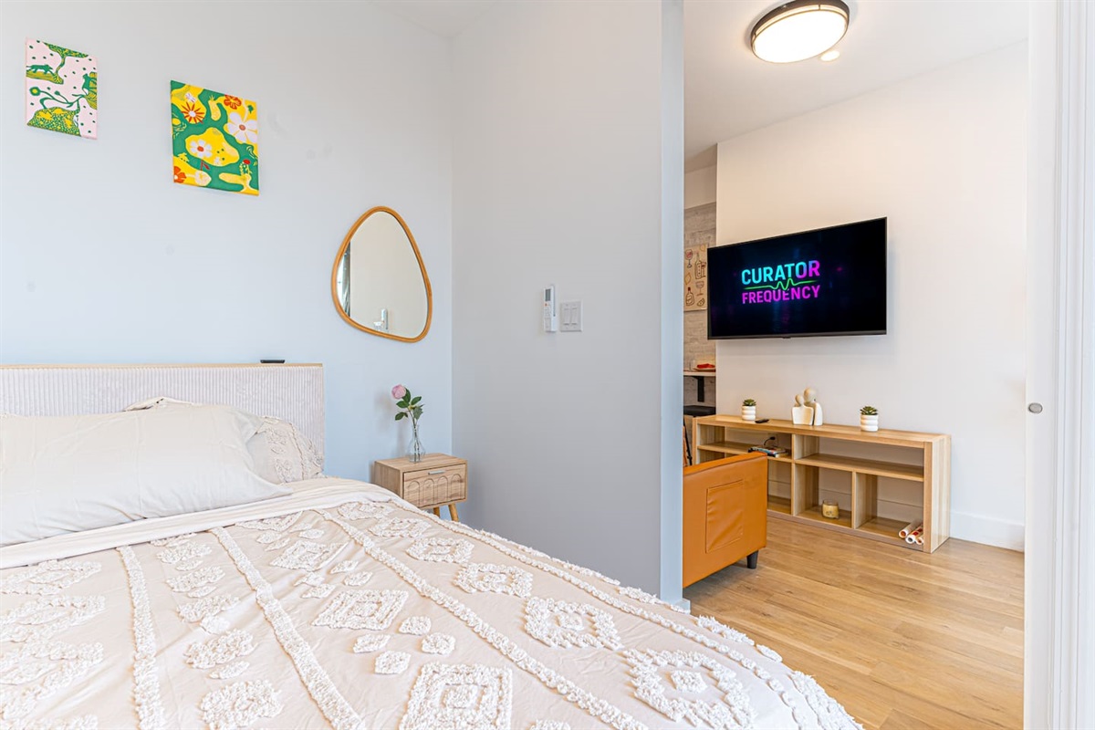 Comfortable bedroom with a mounted TV and plush bedding — wind down in your private Brooklyn haven.