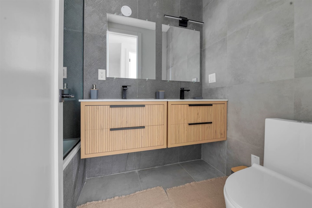 Sleek bathroom with a double wood vanity, wide mirror and modern tilework — fresh and spa-like.