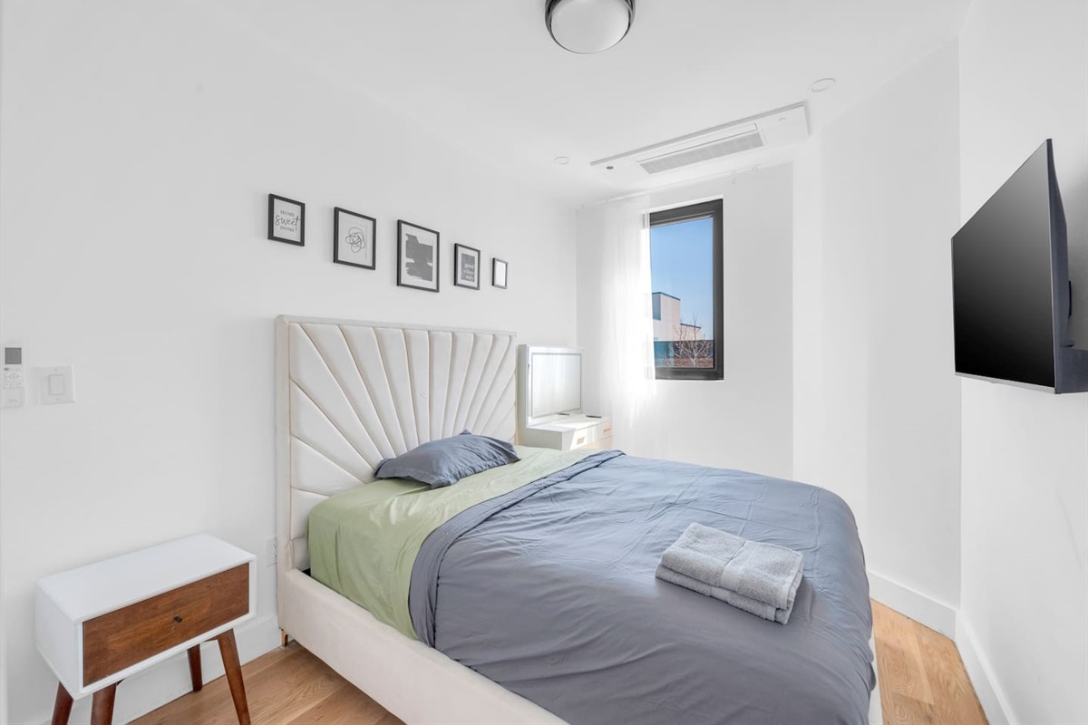 Restful bedroom with an upholstered headboard, soft linens and a wall TV — quiet, comfortable nights.
