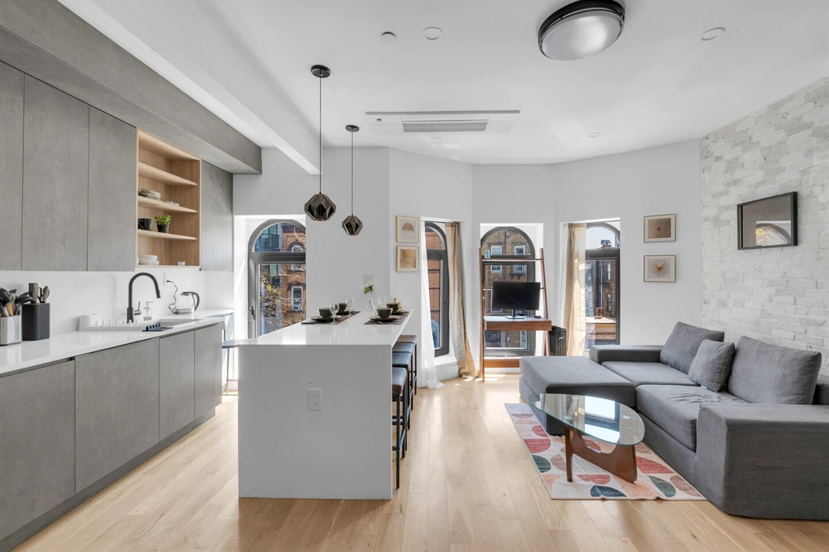 Bright, modern open-concept living and kitchen with a sleek island and arched windows — your stylish Brooklyn retreat.