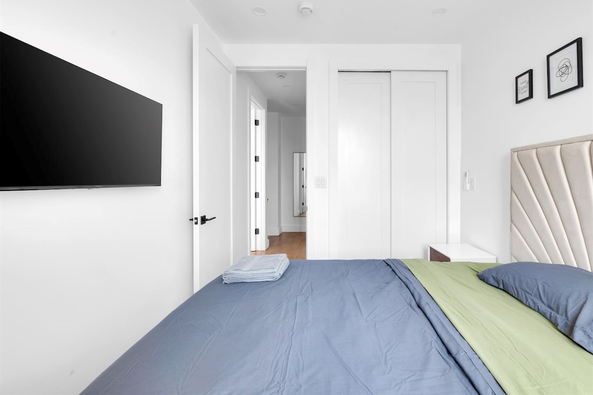 Bedroom corner with a wall-mounted TV and ample closet storage — keep settled in during your stay.