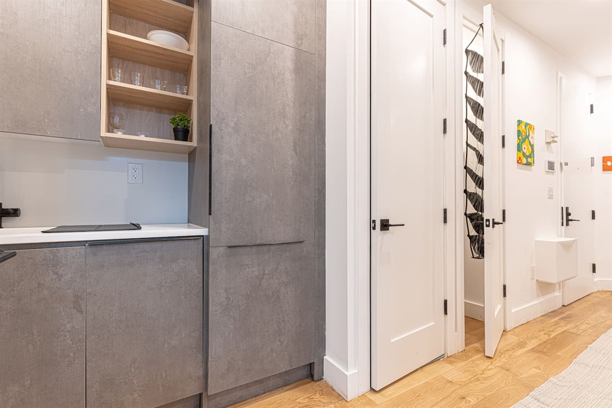 Modern kitchenette with grey cabinetry, cooktop and clean prep space — everything you need to cook in between NYC advent
