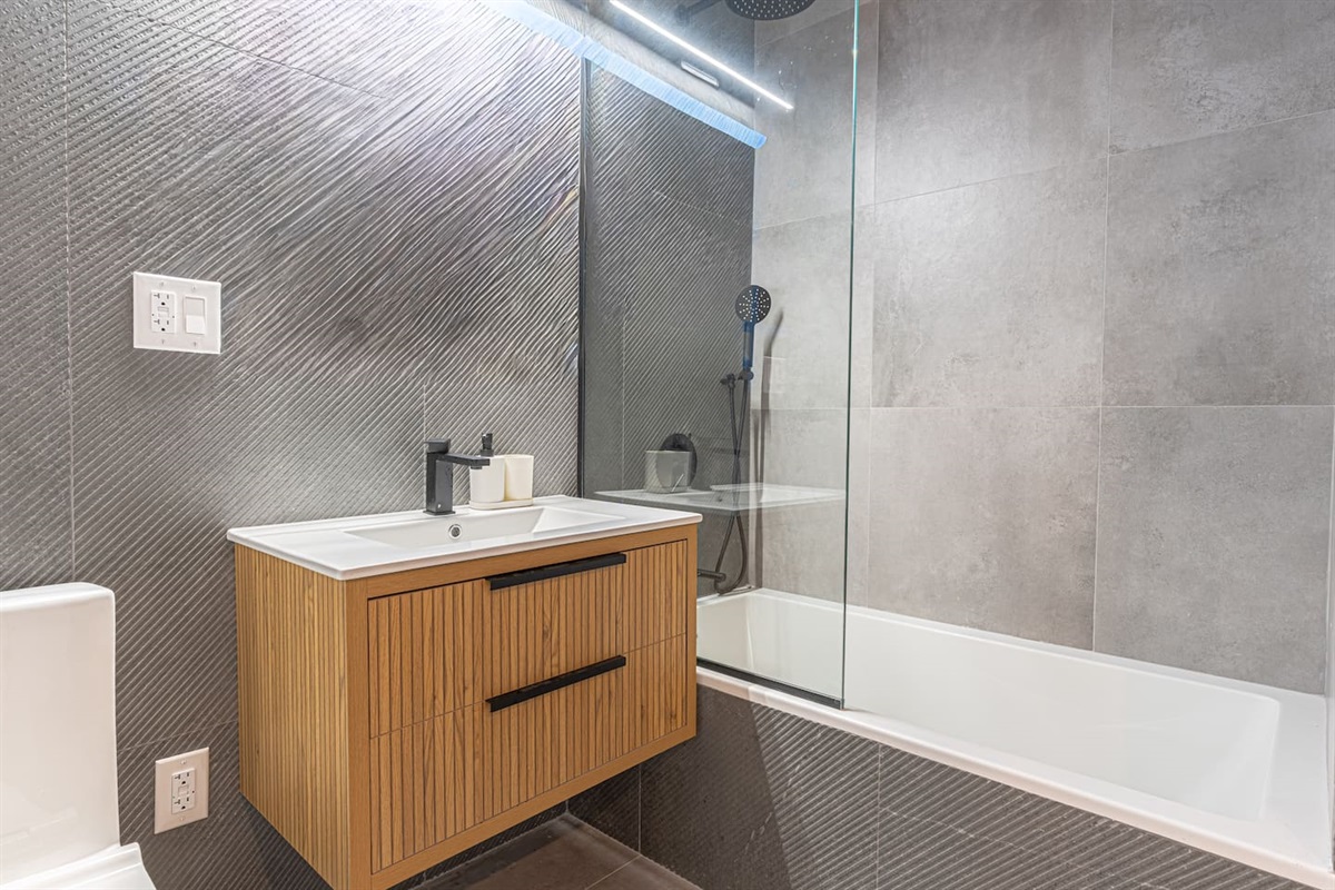 Clean, contemporary bathroom with a sleek wood vanity and fresh fixtures — spotless and ready for your stay.