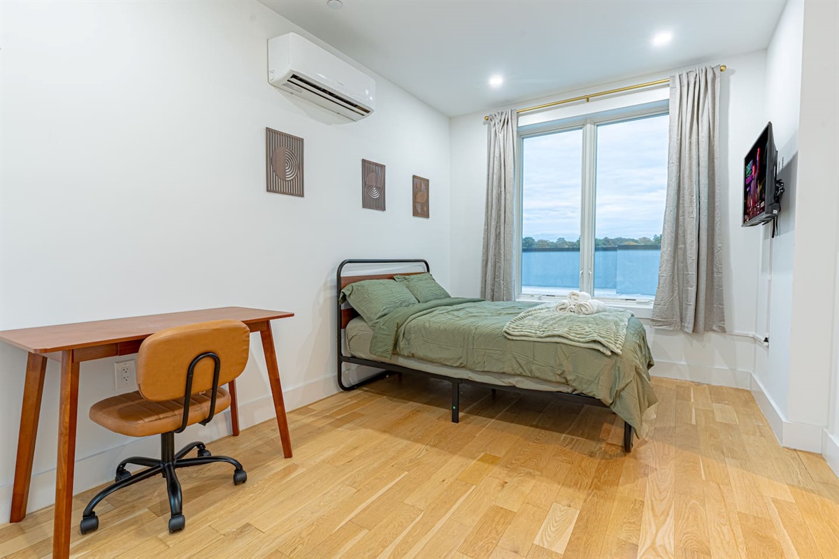 Full bedroom equipped with work desk and bathed in natural sunlight for productivity.
