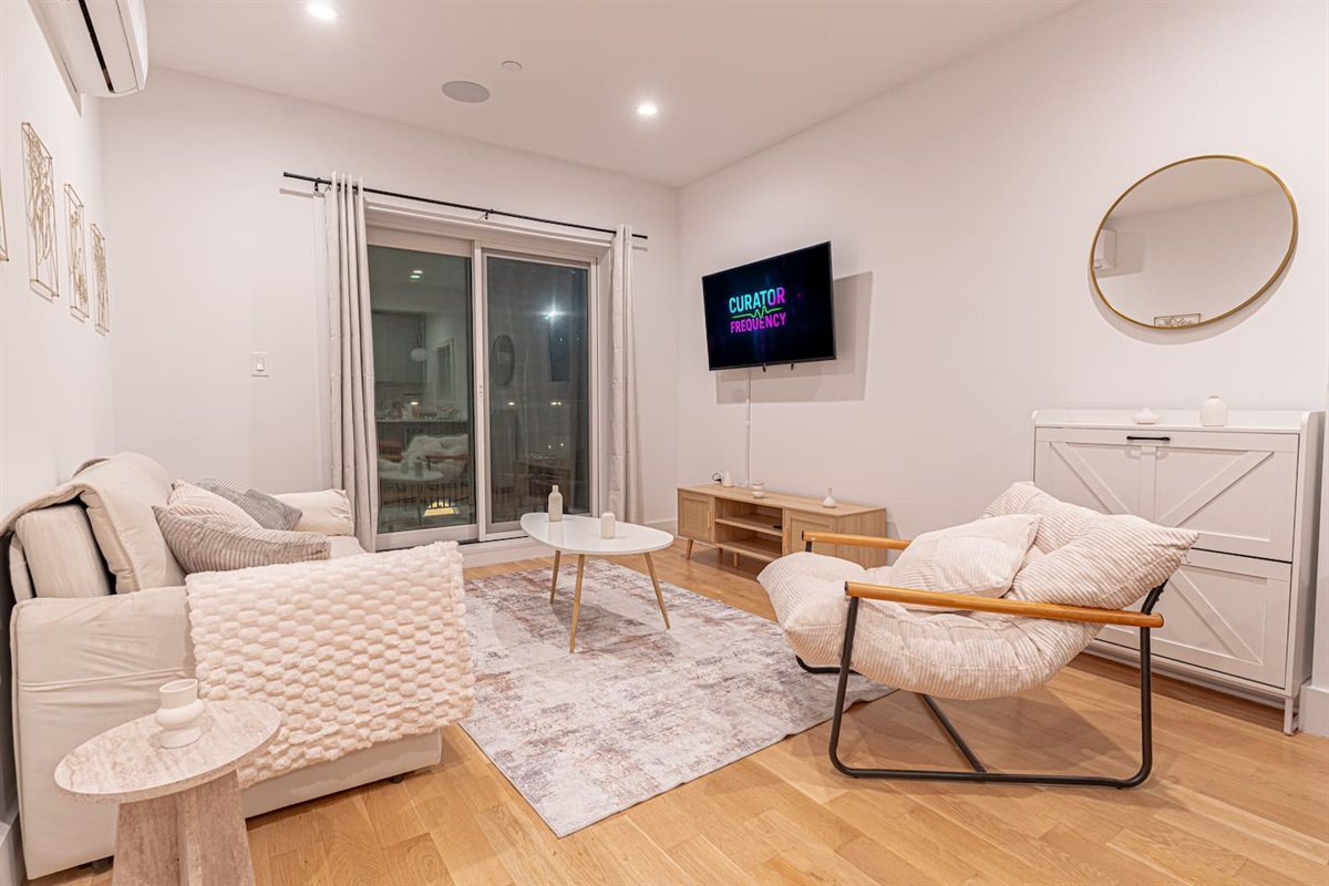 Boho-style living room with plush seating, smart TV and balcony access; relax in your Bushwick hidea