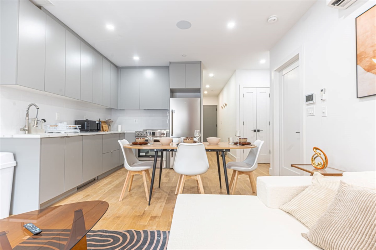 Modern kitchen with cabinets, stainless appliances, and a dining table with white chairs.