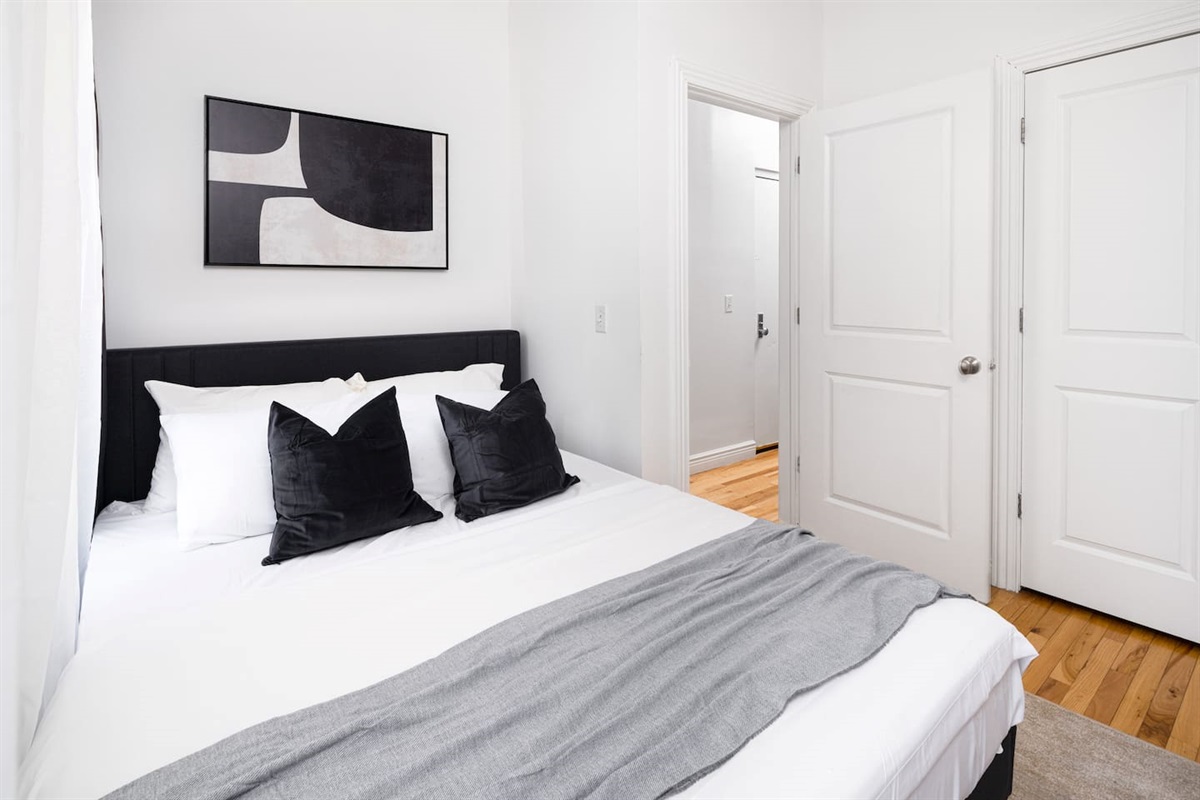 Monochrome bedroom with abstract art, black headboard, and minimalist styling