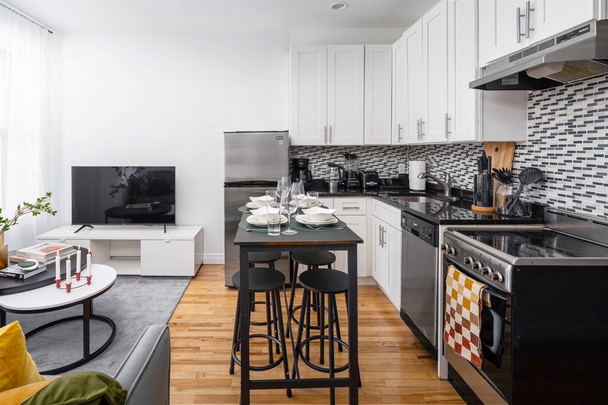 Open kitchen/living space with island dining, cozy sofa, and natural light