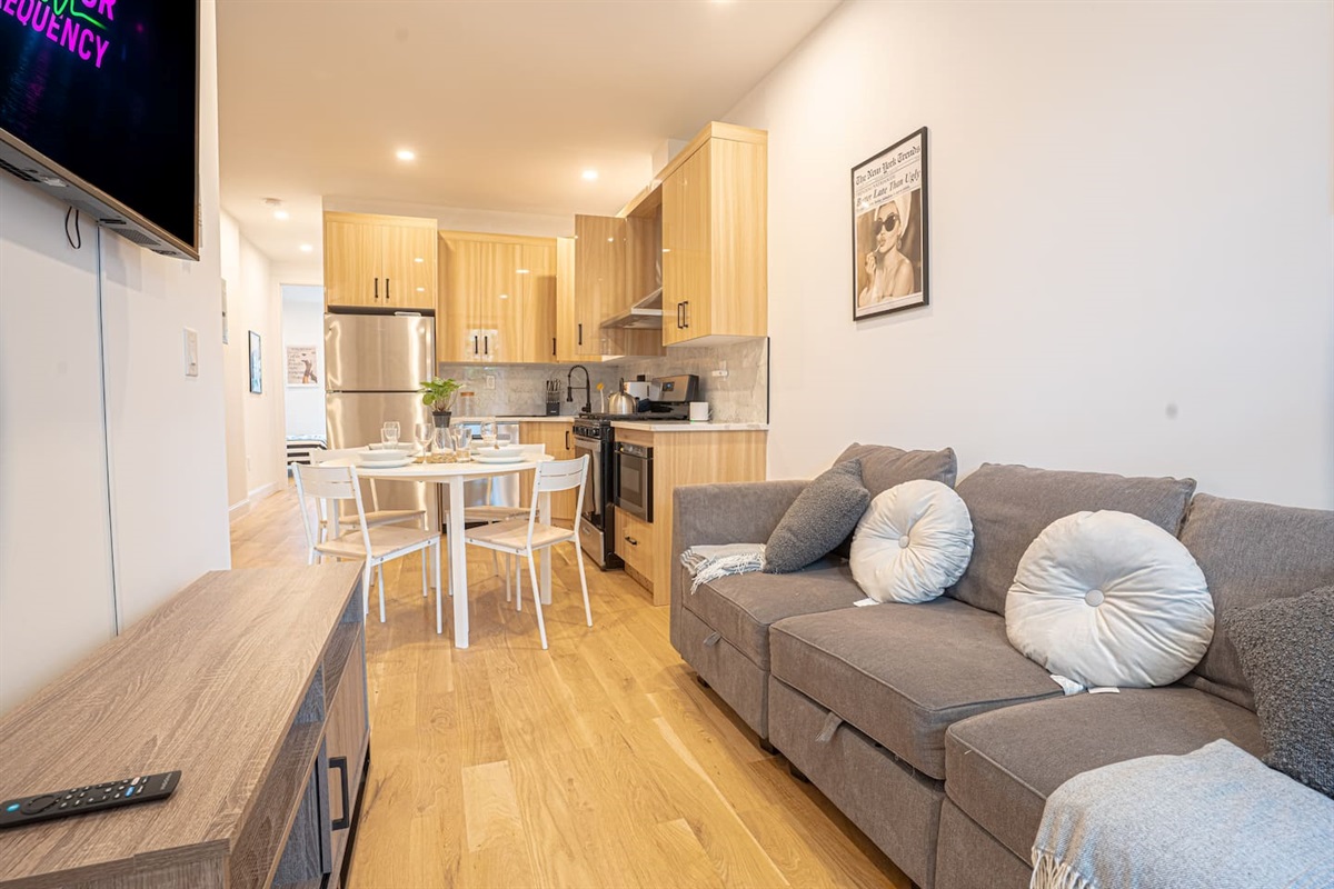 Cozy living area with modern kitchen, dining for four, plush sofa and warm wooden flooring.