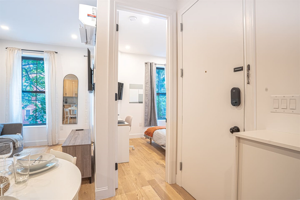 Bright entryway featuring smart lock, leading to open living and bedroom areas for secure welcome.