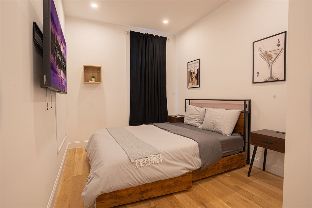 Modern bedroom offering queen bed, TV and sleek minimalist design for a polished retreat
