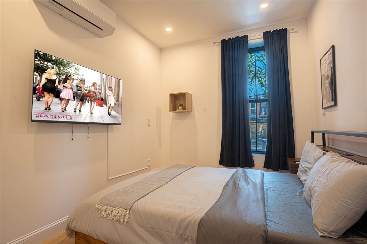 Cozy queen bedroom with smart TV, blackout curtains and tranquil décor for restful nights