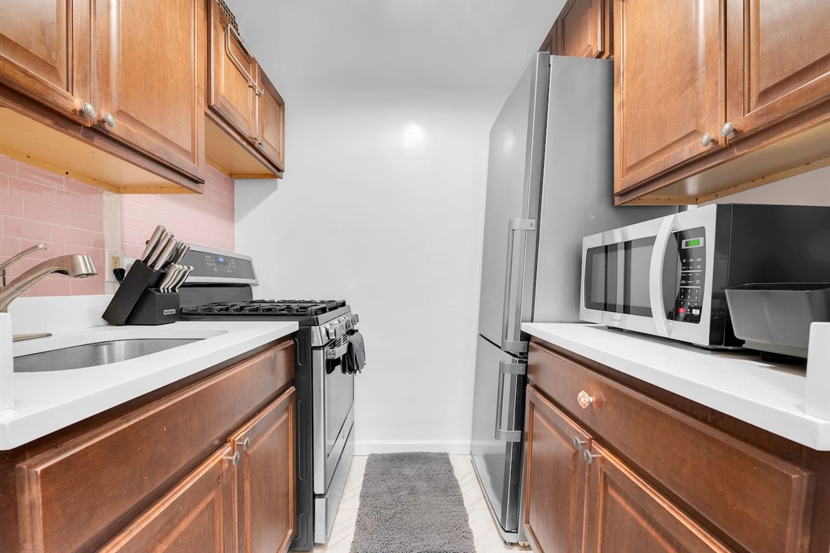 Fully equipped kitchen with gas stove, full-size fridge, and ample cabinets — cook in or grab dinner on nearby 5th & 7th