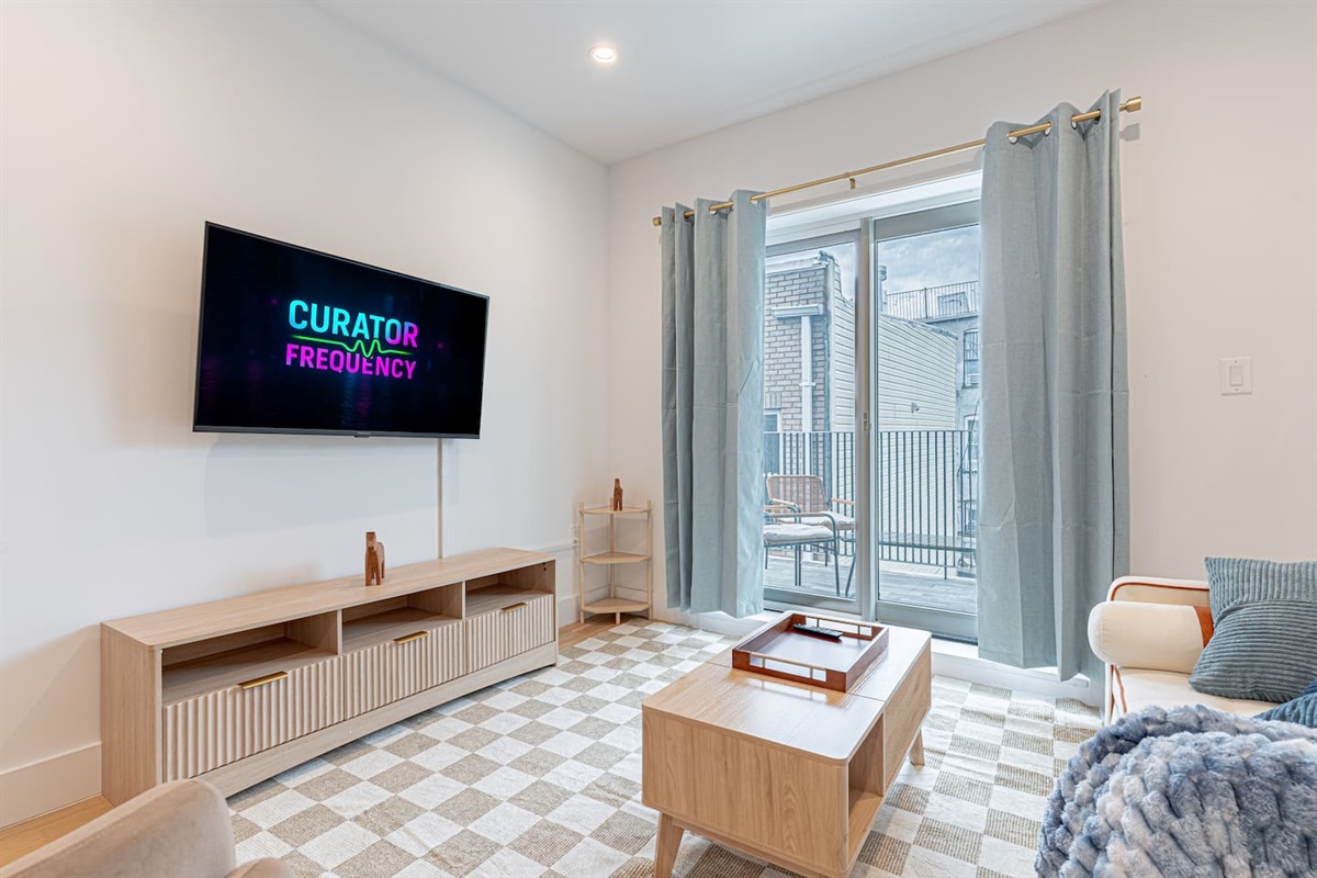 Smart TV living Smart TV viewing area with cozy seating in bright Scandinavian Bushwick 1BD apartmen