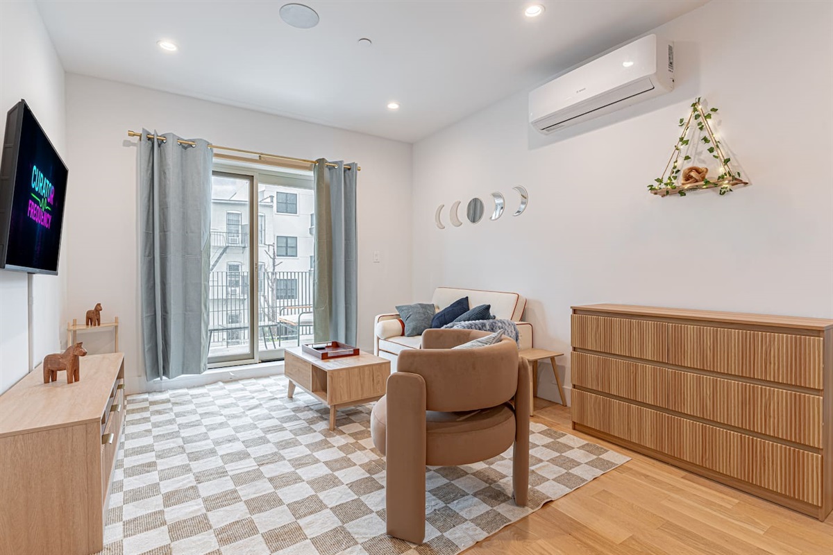 Living room with smart TV, armchair and sofa in bright Scandinavian Bushwick balcony loft