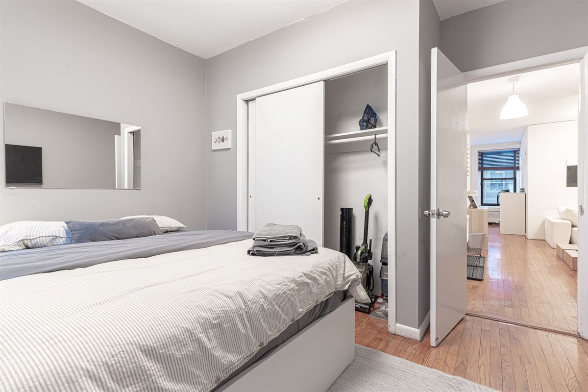 Restful primary bedroom with plush queen bed, blackout window treatments, and smart TV — quiet sleep in the middle of Ma