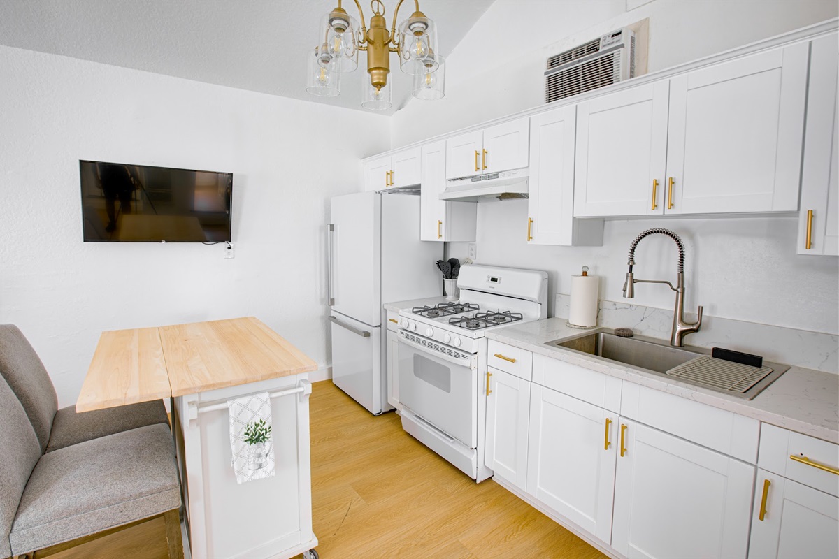 Fully equipped kitchen with crisp white cabinetry, full-size sink, and ample counter space — cook in with ease.