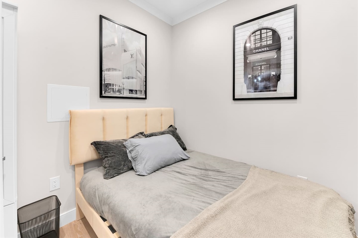 Primary bedroom with plush queen bed, blackout treatments, and smart TV — quiet sleep in midtown Manhattan.