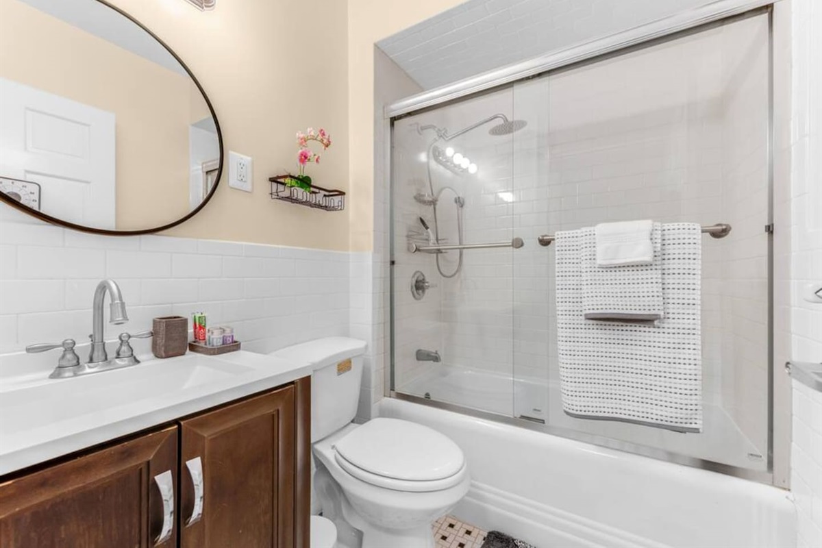 Clean, modern bathroom with tub-shower combo, fresh towels, and toiletries provided.