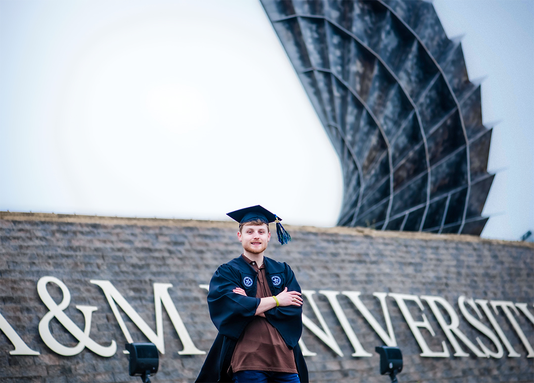A graduate of Texas A & M onfront of their brick sign on the Gulf.