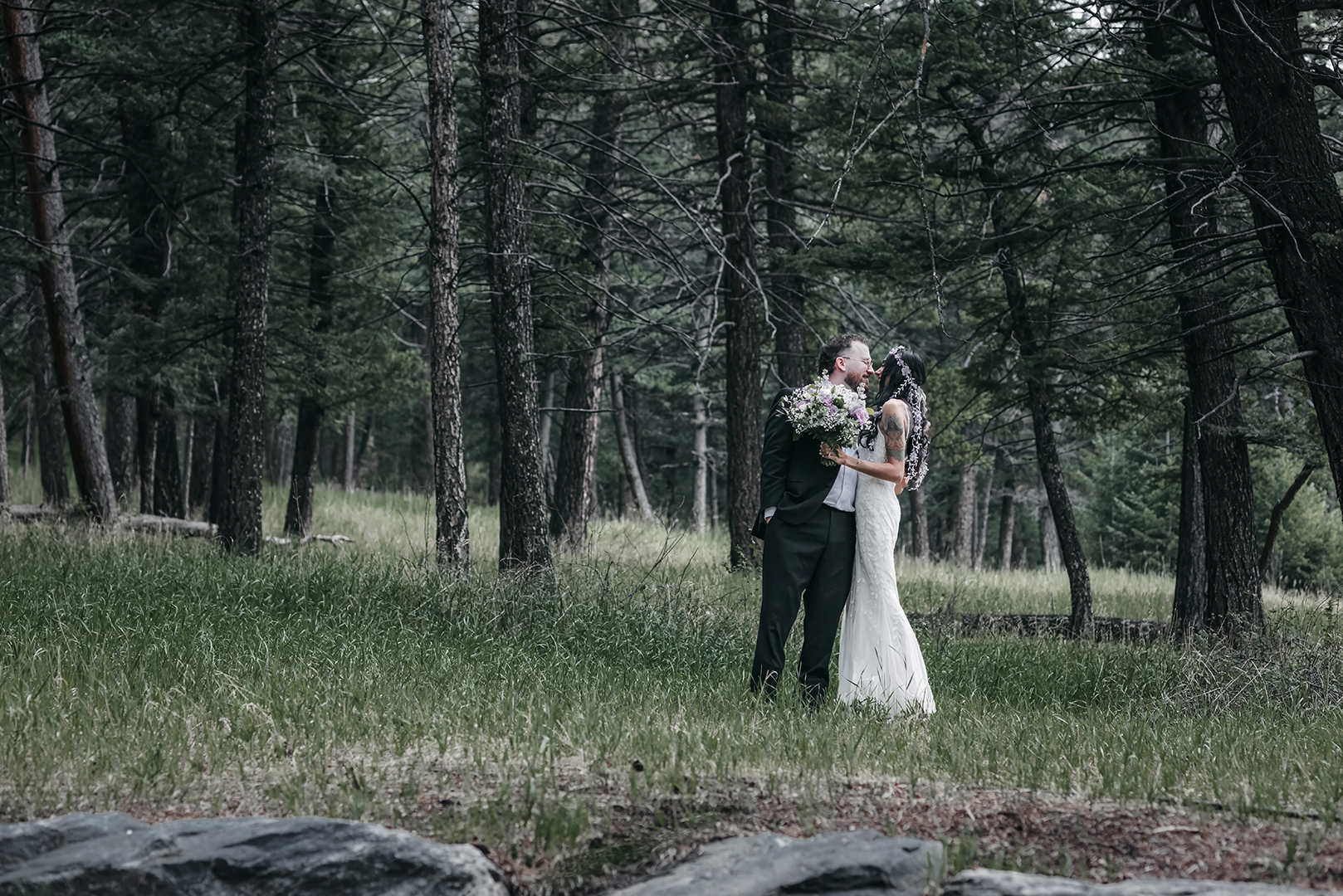 A bride and groom facing eachother in a forest of Pines of Colorado
