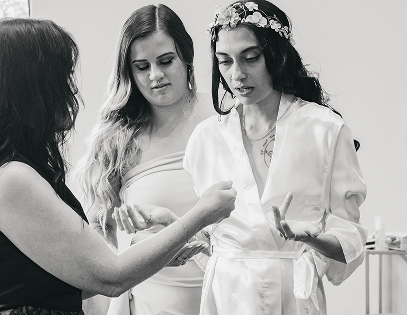 A black and white image of the bride realizing her mother in law has the necklace she wanted to wear to accessorize her dress.