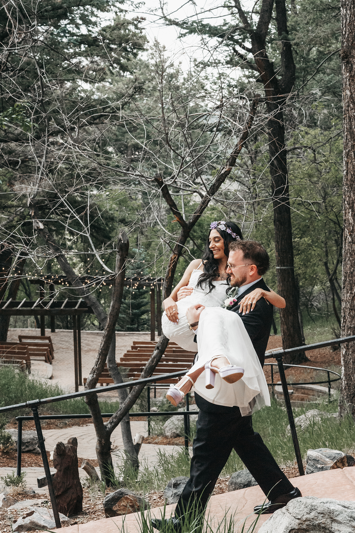 A professional image by Shutterpix Photography of the groom carring his bride in the pines of Golden, Colorado