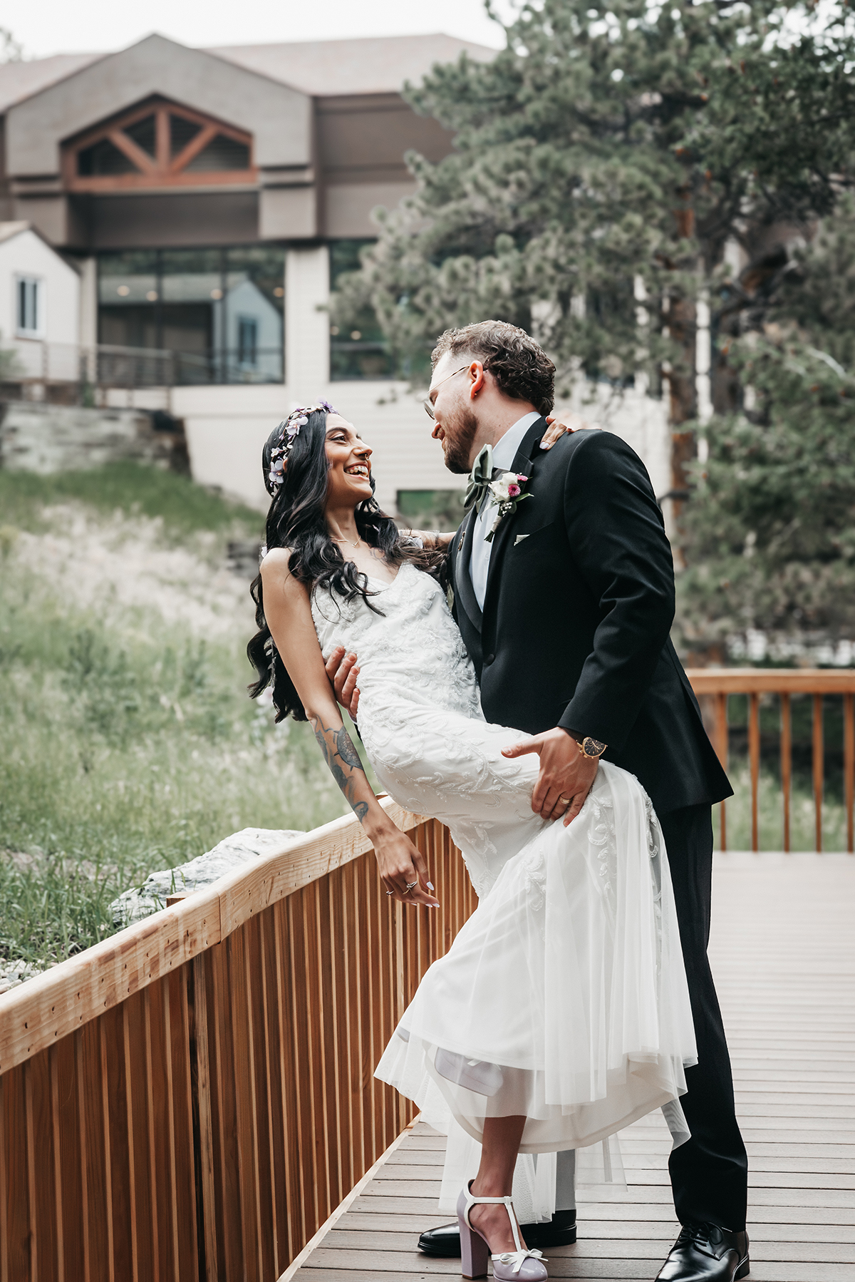 A couple  geniunely smiling at eachother dipping the bride with their wedding venue, Wedgewood at The Pines in Golden Colorado.