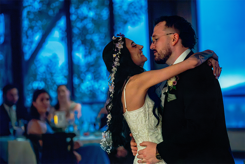 A bride and groom wrapped in eachother's arms on the dancefloor at their wedding reception.