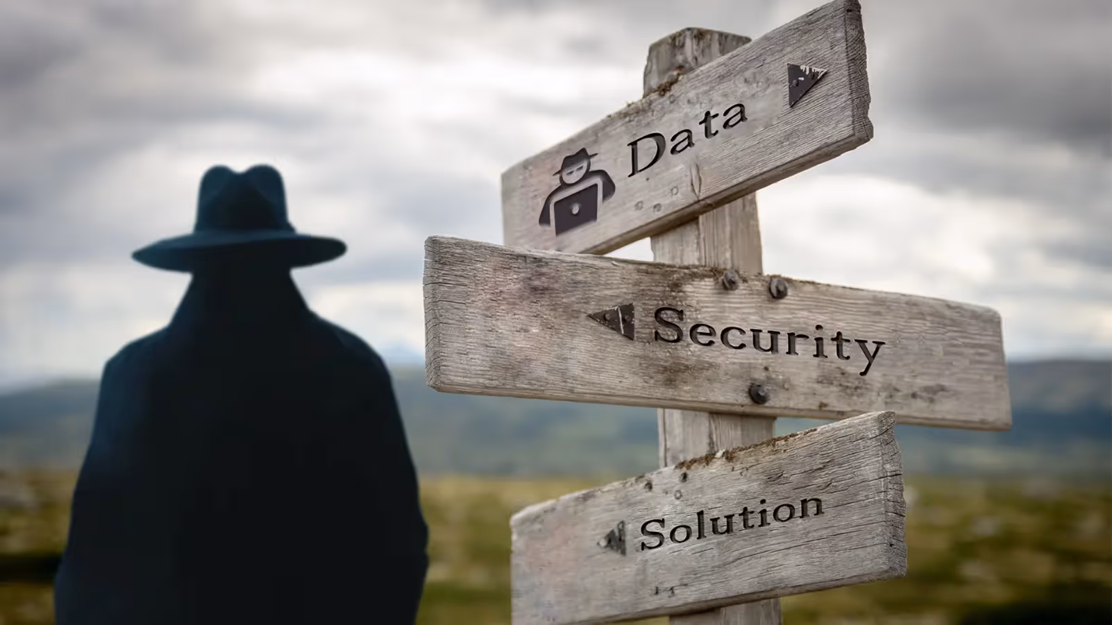Wooden signpost with "Data," "Security," and "Solution" pointing in different directions, with a mysterious figure in the background.