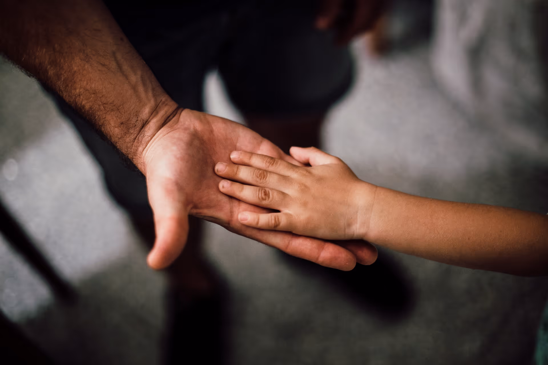 Main d'enfant tenant la main d'un adulte illustrant les solutions d'aide à la parentalité en entreprise
