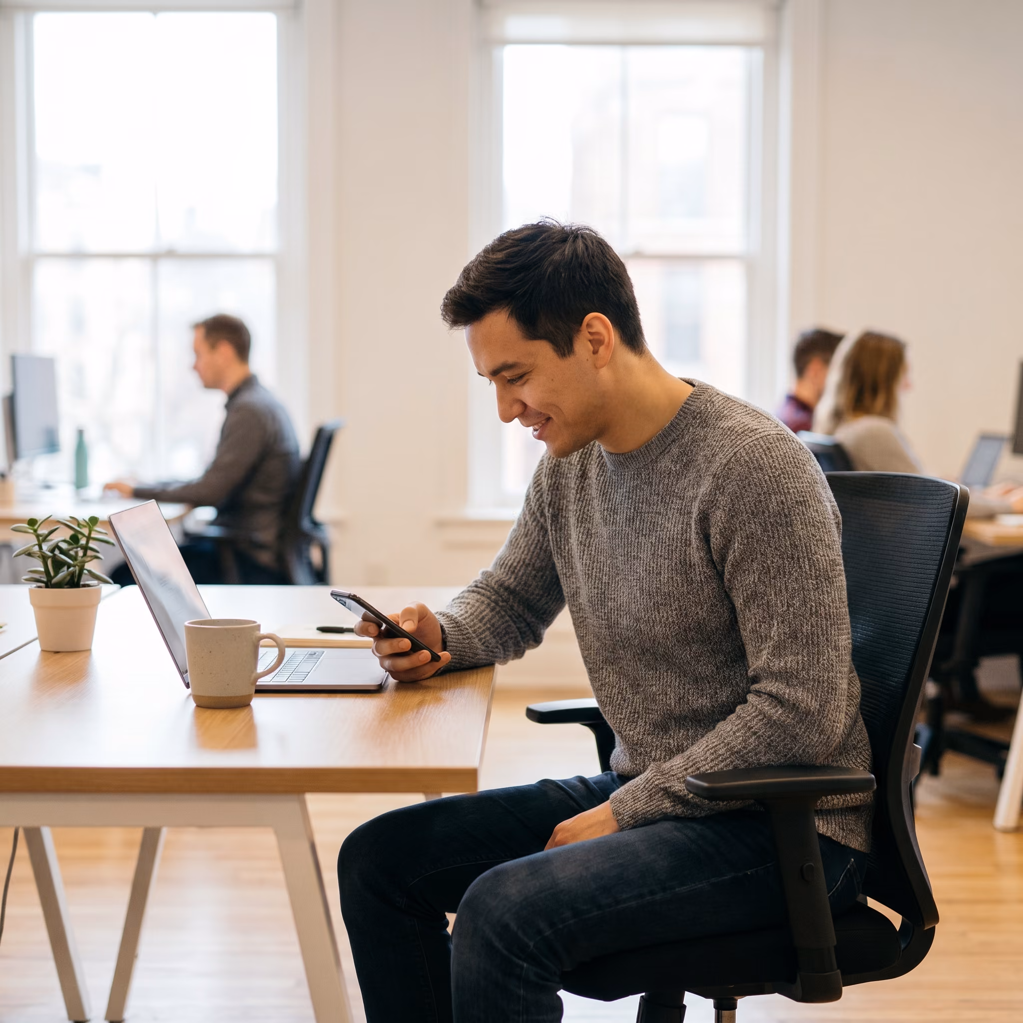 Salarié consultant une notification sur son smartphone dans un espace de travail moderne