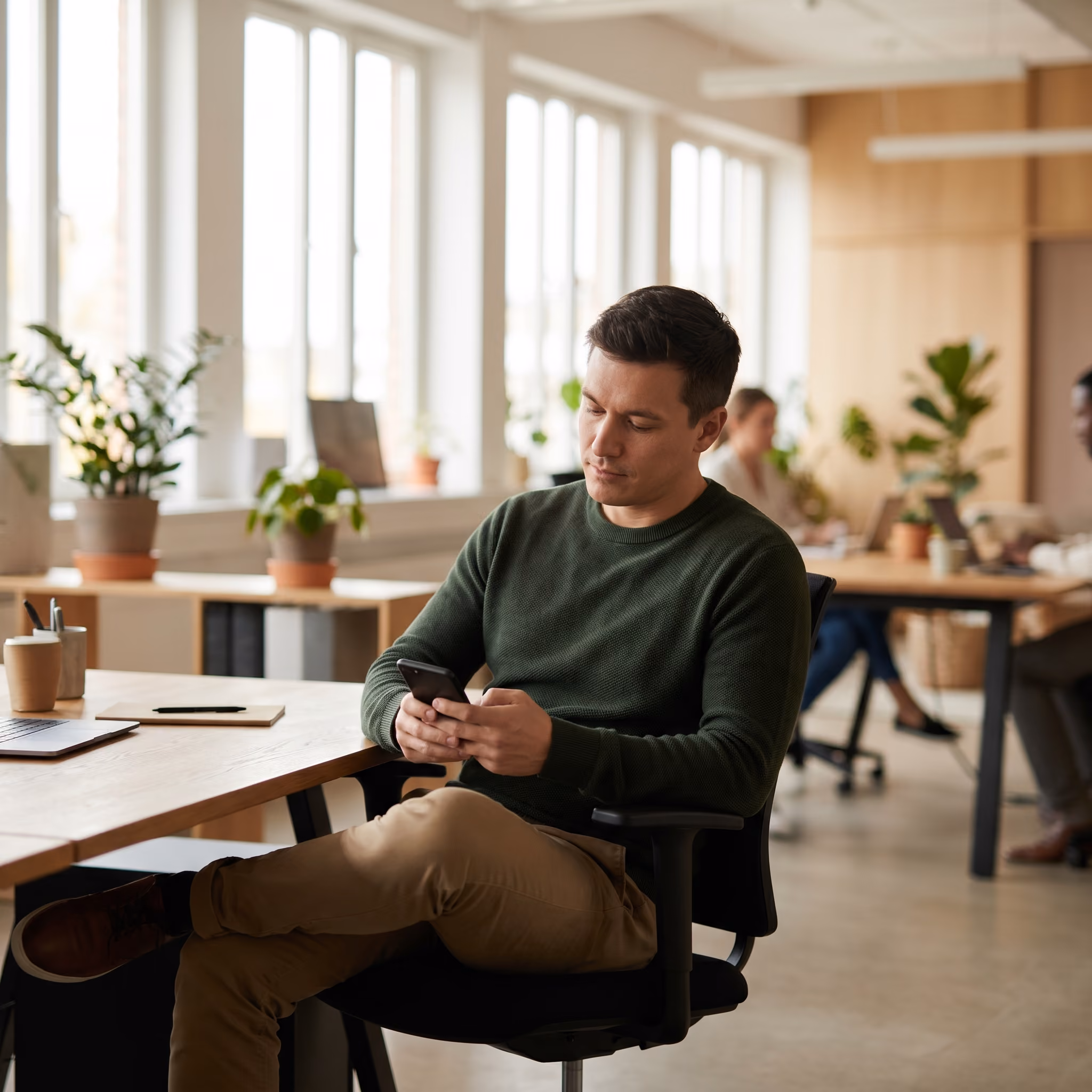 Collaborateur consultant ses avantages salariés sur smartphone dans un open space moderne
