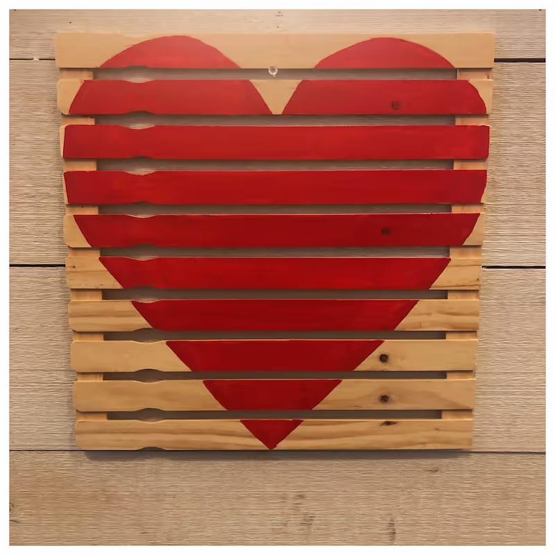 A wooden pallet has a heart painted at full size on it's surface. Between the slats, the background is visible. 