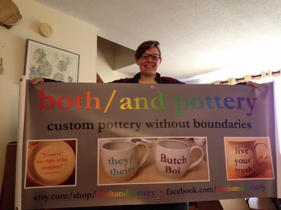 Ryan Ambuter holding a both/and pottery banner