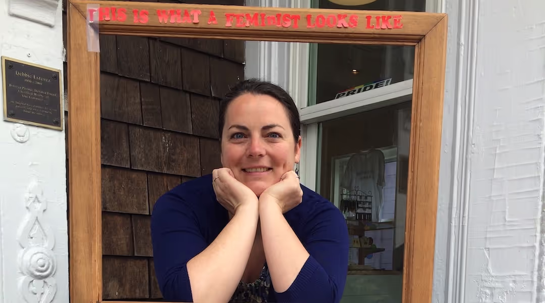 Reverand Kate Wilkinson posing in a frame that says "This is what a feminist looks like"