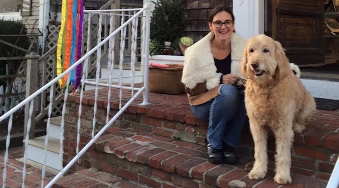 Janine Evers and a dog seated on the front steps of Womencrafts in Provincetown, MA