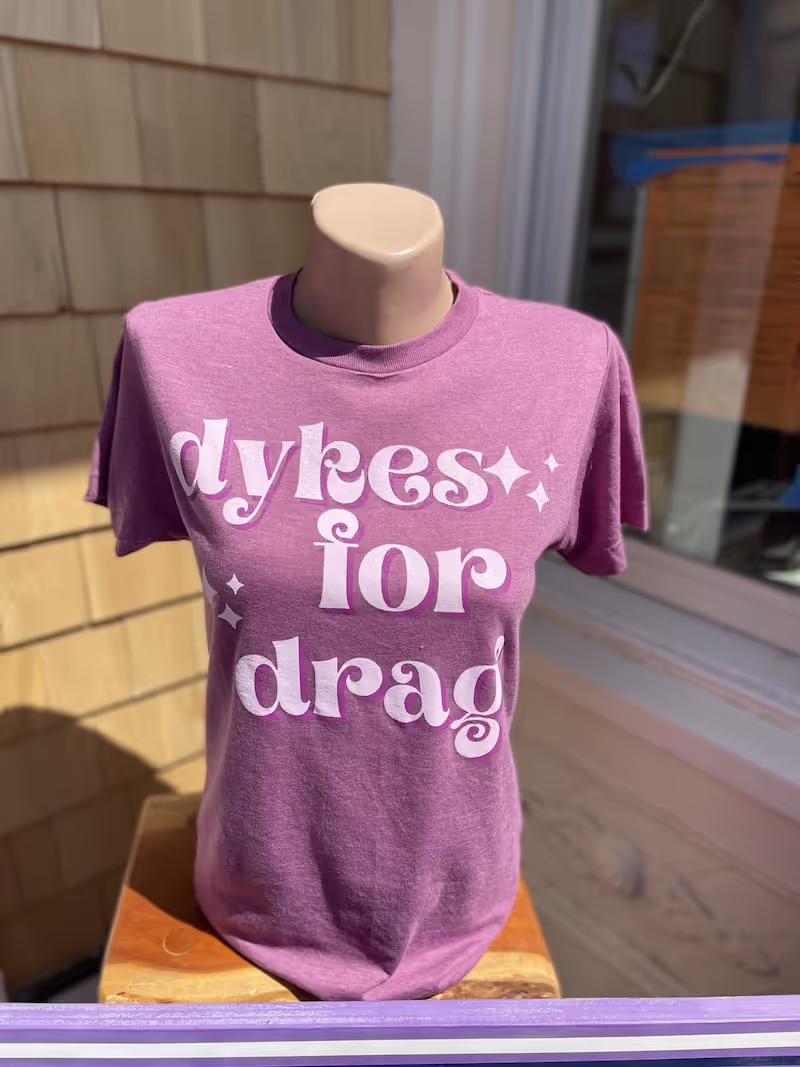 Purple t-shirt displaying the words "Dykes for Drag"