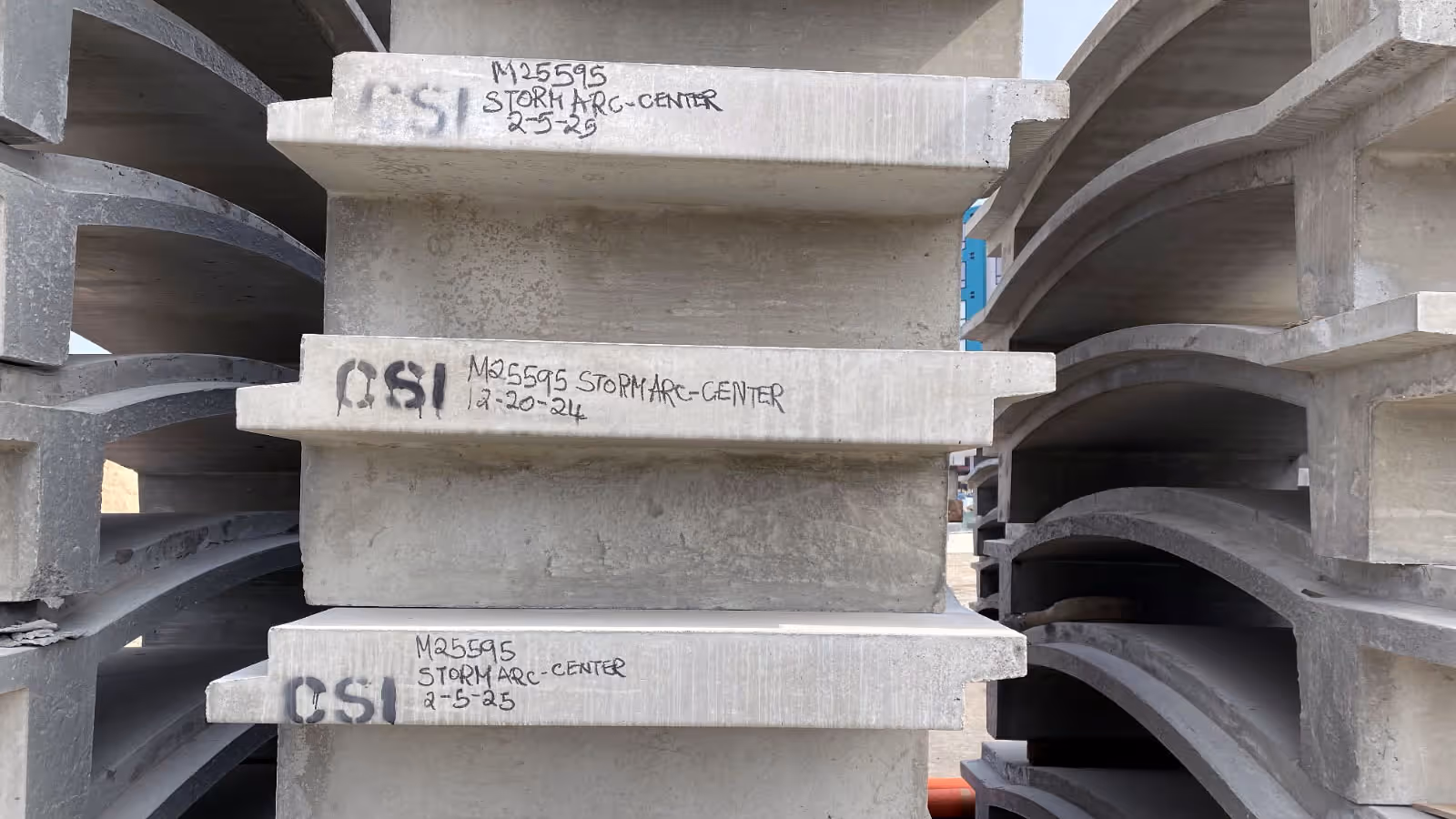 Stacks of precast concrete segments labeled with identification numbers and text, arranged vertically at a construction site.