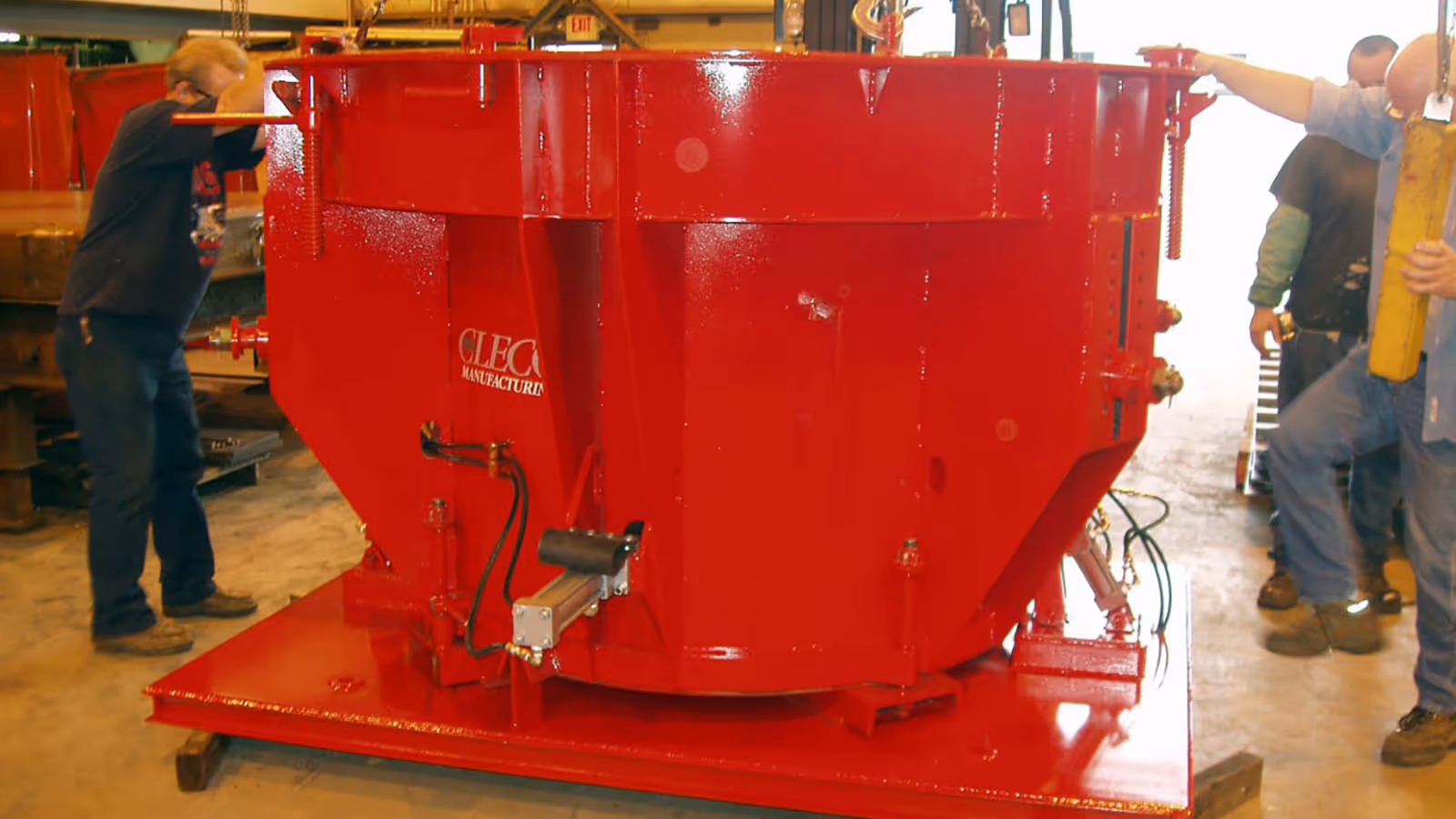 Large red industrial machine with control mechanism, placed on a metal platform, surrounded by several workers.