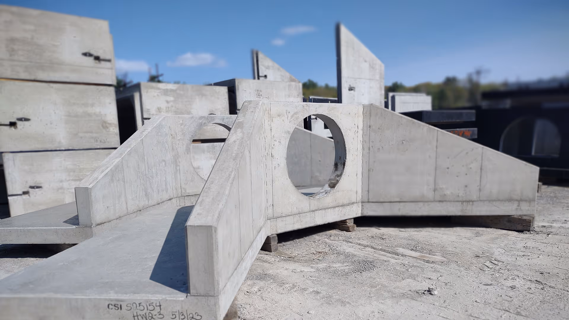 Large precast concrete structure with circular openings on a construction site under a clear sky.