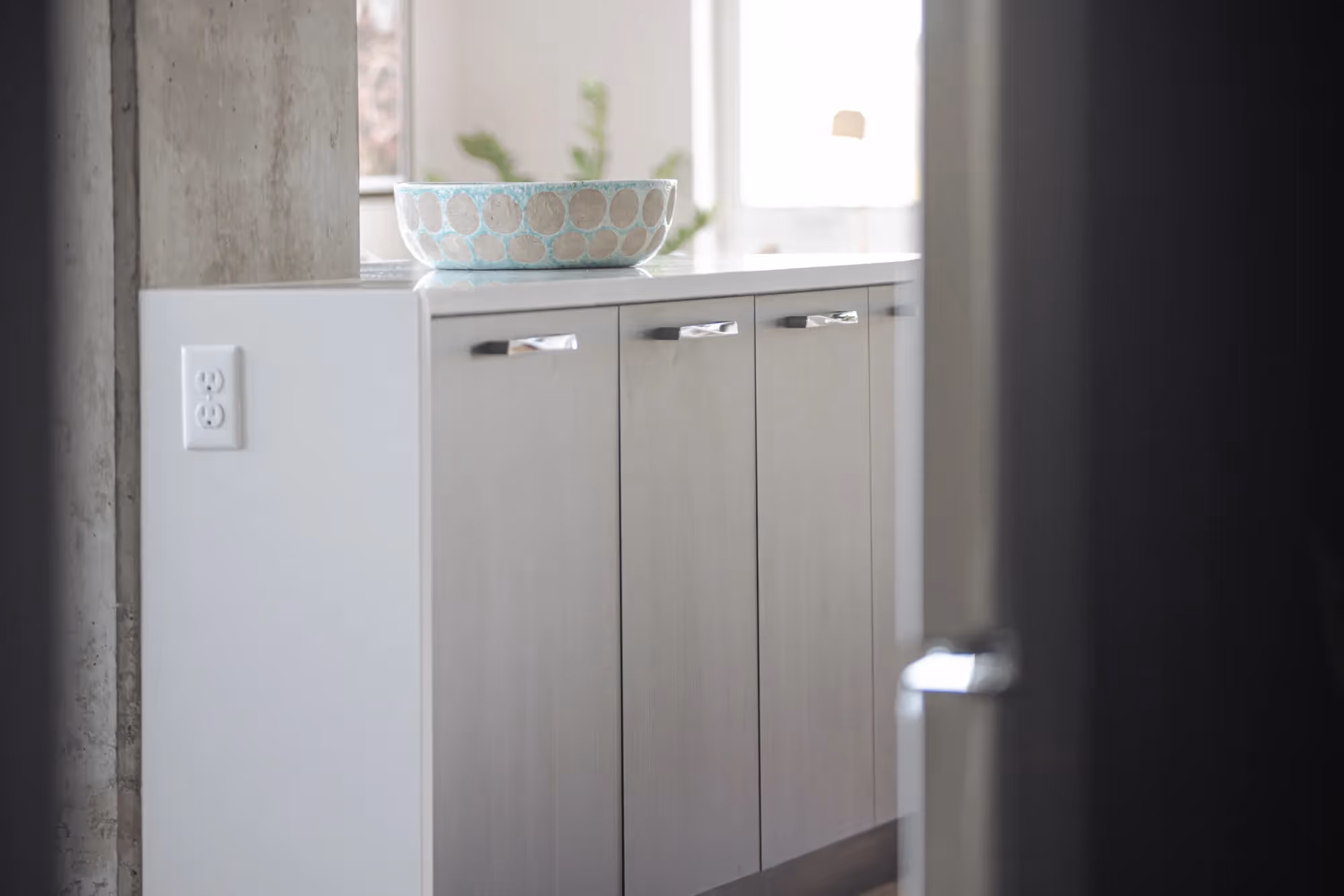 Close-up of kitchen or bathroom cabinets with a decorative bowl on top, featuring modern design elements at The Julian apartments.