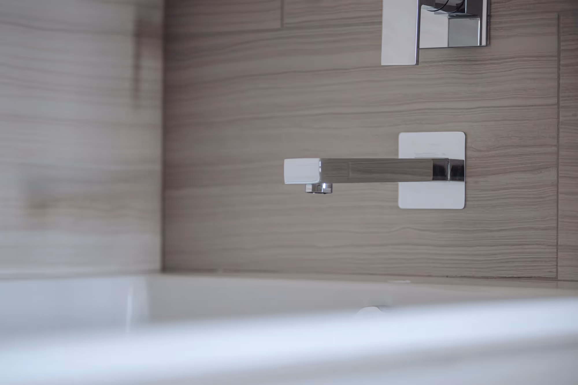 Modern bathtub faucet and tile surround in a bathroom at The Julian apartments in Sloans Lake, Denver, showcasing sleek fixtures.