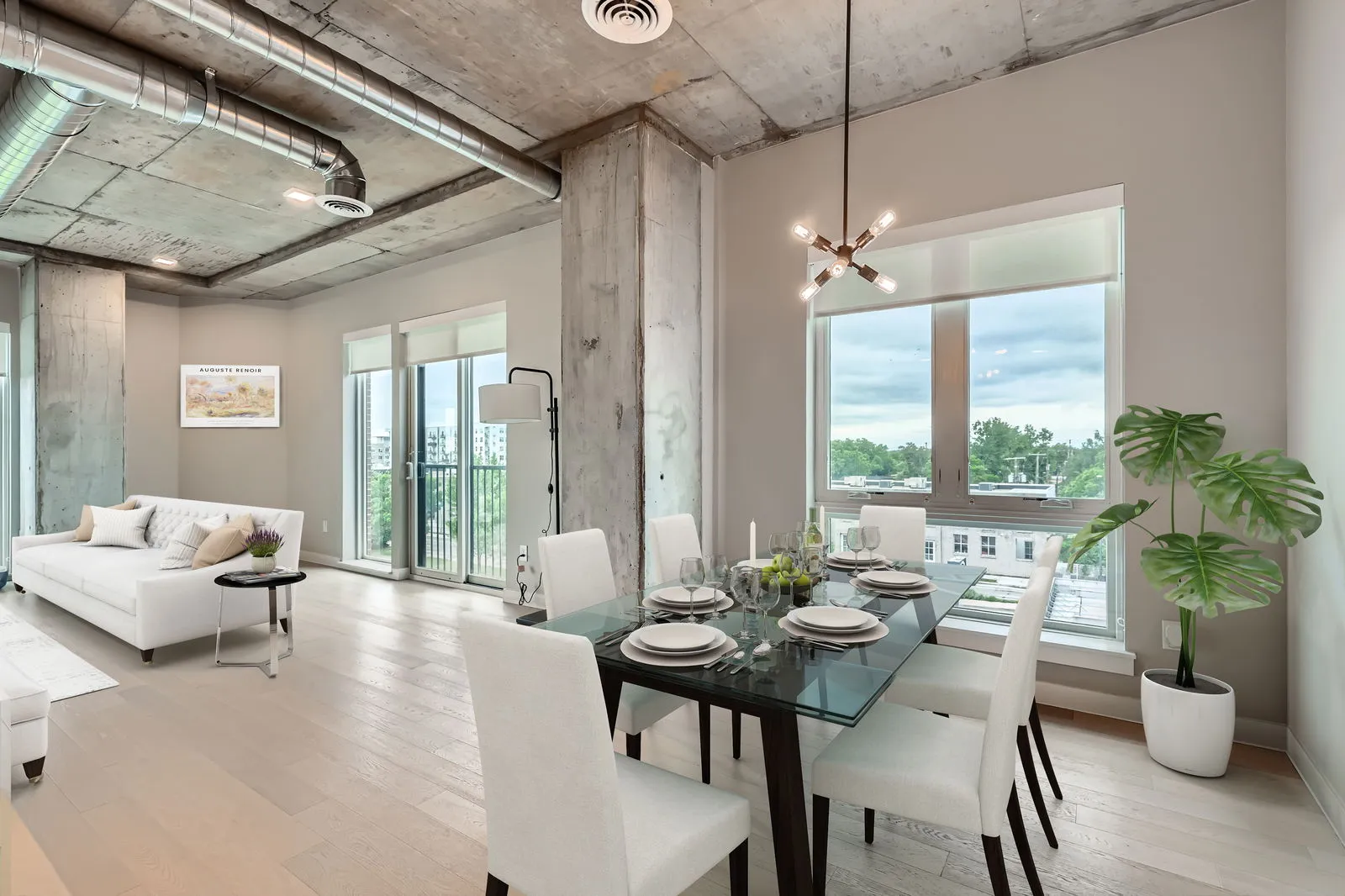 Contemporary dining room and living area with exposed concrete ceiling and large windows overlooking the city from The Julian apartments in Sloans Lake, Denver.