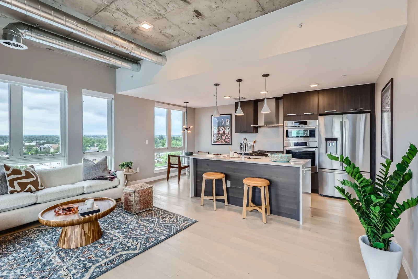 Spacious open-concept living area and kitchen in a luxury apartment at The Julian in Sloans Lake, Denver, with concrete ceilings, large windows, and a modern aesthetic.